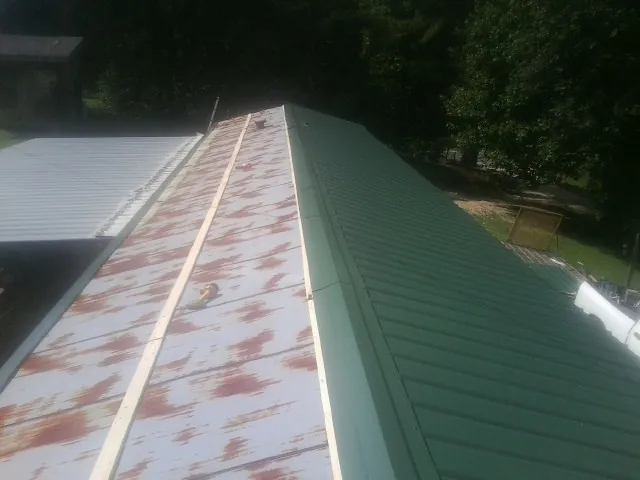 Old rusted panels beside newly installed green metal roofing — Wind Damage Roof Repair by Roofing Brothers in Millersville