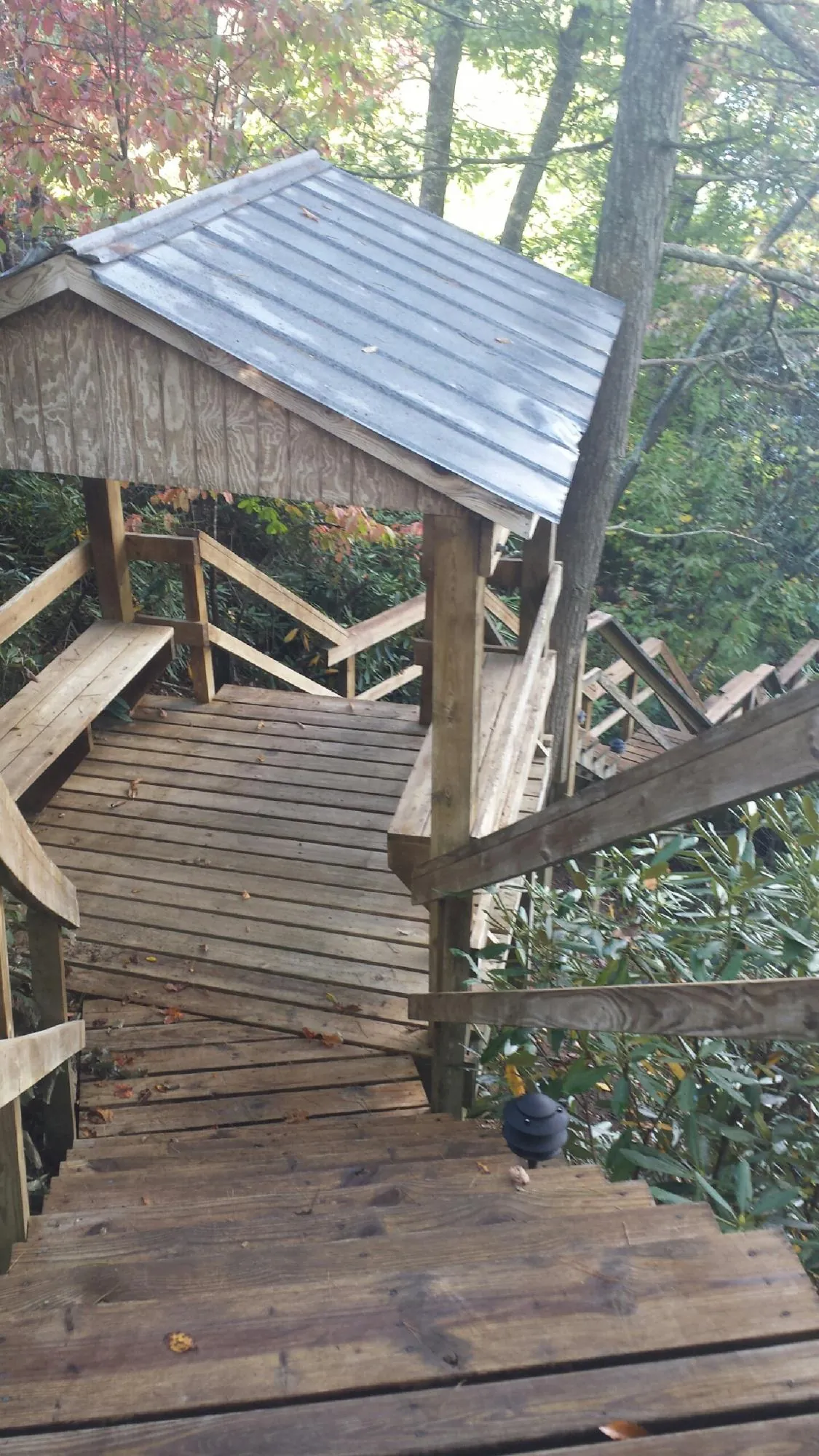 Metal roofed shelter over wooden steps on a wooded walkway — Skylight Repair & Installation work by our crew in Millersville